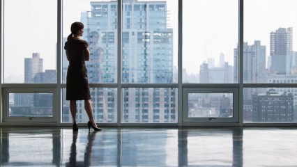 Femme d'affaires face à une verrière d'immeuble surplombant la ville