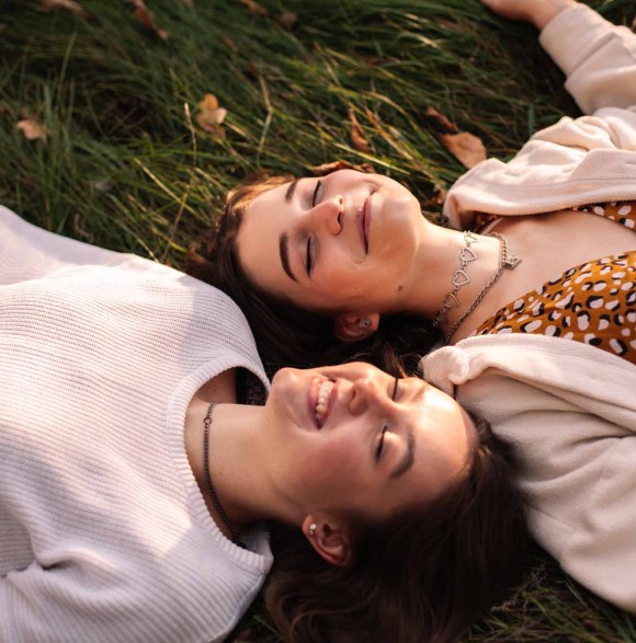 Deux filles allongées dans l'herbe, avec le sourire. 